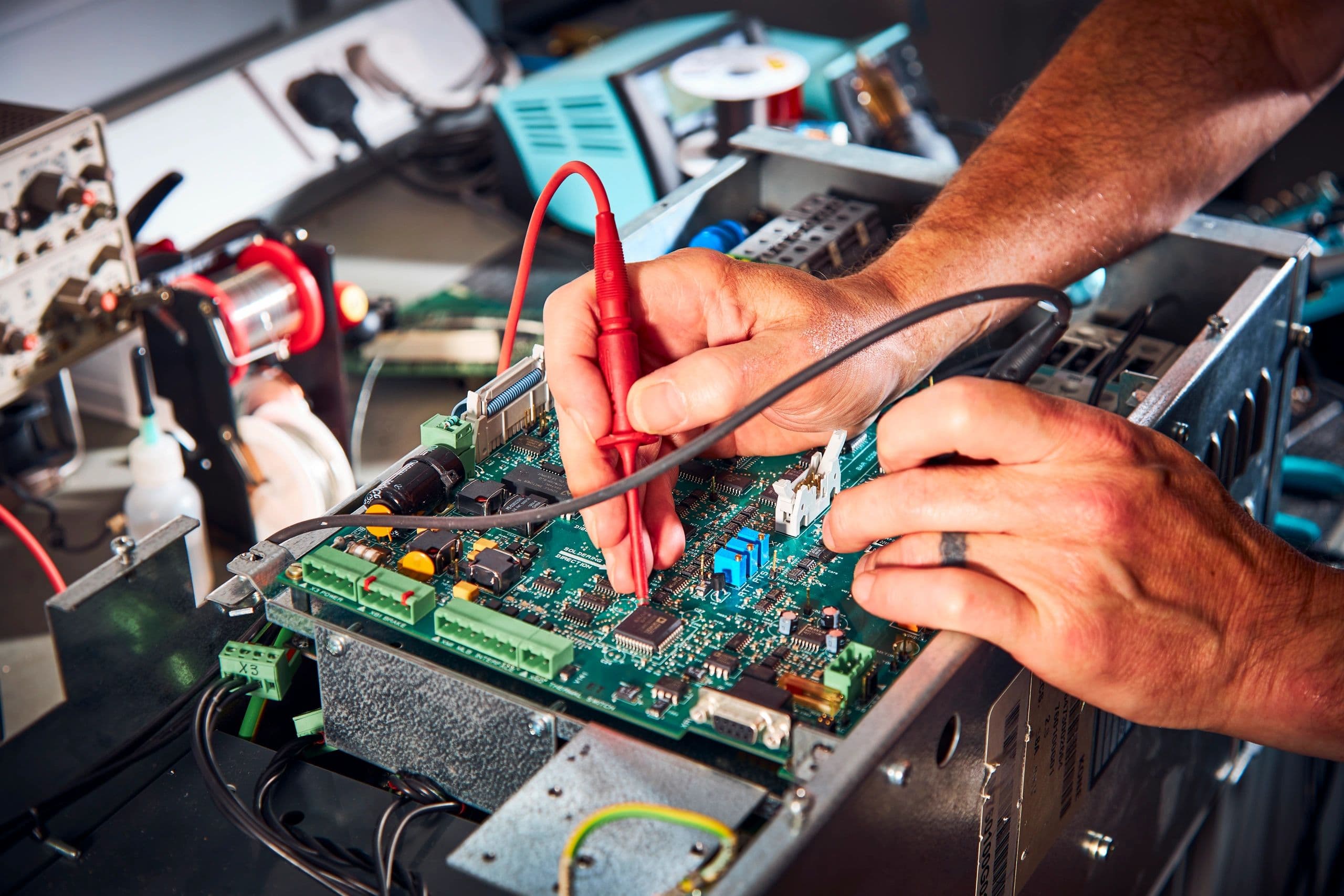 Hands probing and testing an elevator circuit board