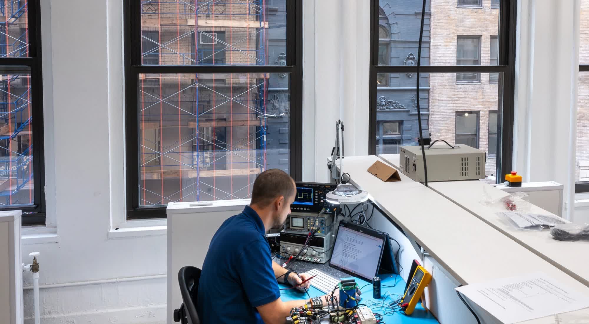 Engineer testing elevator electronics at a workshop bench